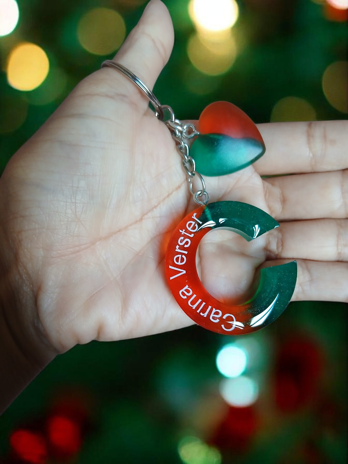 Misty Crafts Designs personalised resin keychain with a red and green letter C and heart charm held in a hand
