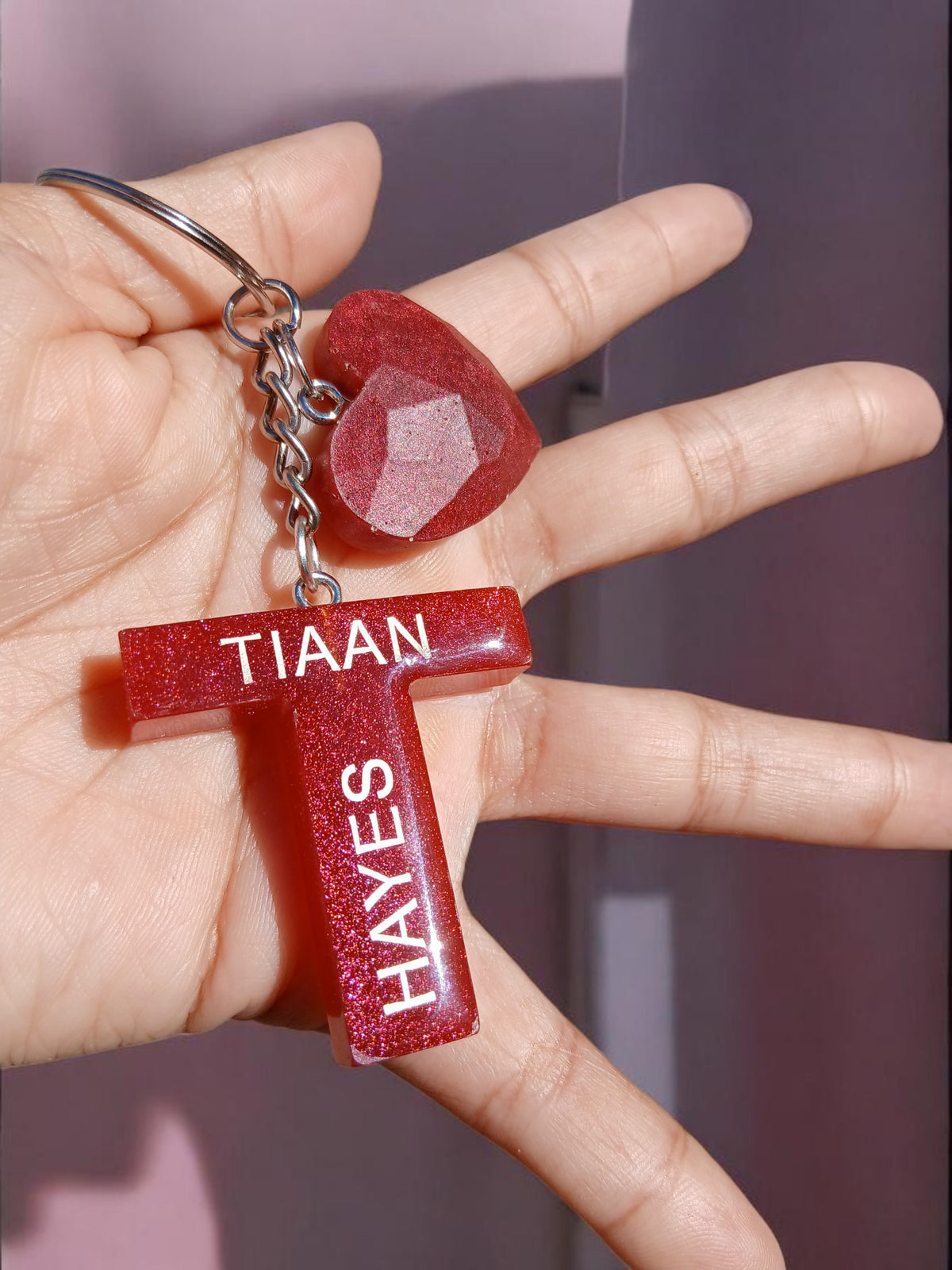 Misty Crafts Designs personalised red glitter resin T-shaped keychain with heart charm held in a hand