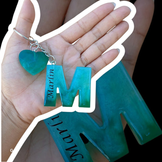 Misty Crafts Designs personalised teal resin letter M keychain with a small heart charm held in a hand